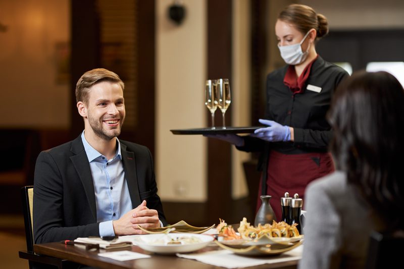 Two young people on dinner being served by a mindful waitress