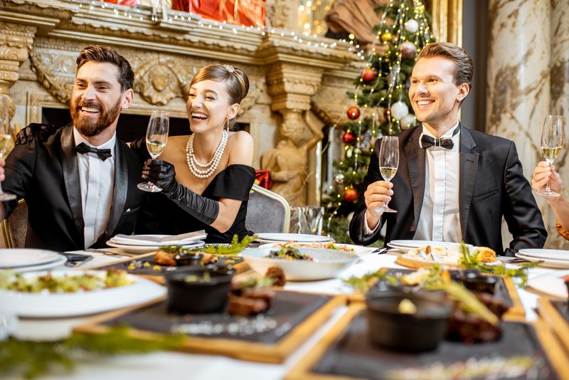 Elegantly dressed people having a festive dinner indoors Elegantly people having a festive dinner indoors