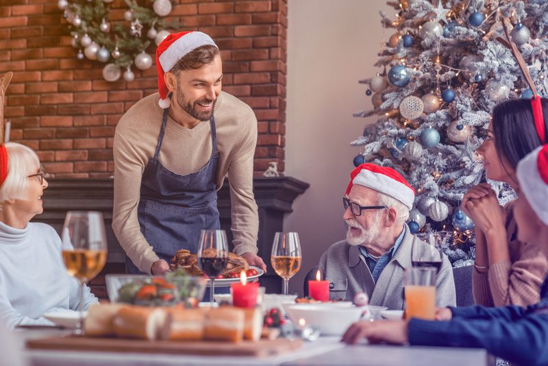 Man bringing out Food at family Christmas meal Man bringing out Food at family Christmas meal